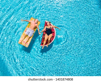 Above vertical view of people old senior couple taking hands with love and having fun on the blue clear swimming pool together enjoying the summer holiday vacation with trendy coloured lilos mattress - Shutterstock ID 1401874808