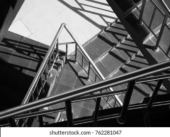 Above view of abstract patterns formed from light and shadow of chrome railings on a zig zag staircase