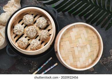 Above view of a bamboo steamer with asian dumplings in a cast-iron pan, horizontal shot on a brown stone background