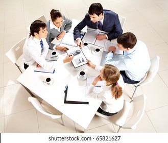 Above View Of Business Team Sitting Around Table And Working With Papers