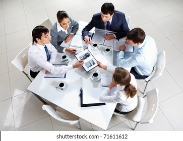 Above View Of Business Team Sitting Around Table And Working With Papers