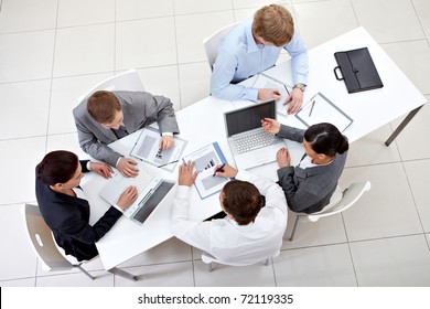 Above View Of Business Team Sitting Around Table And Working