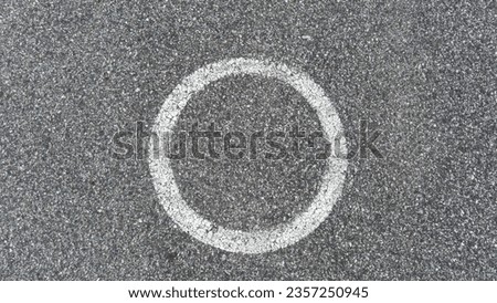 Above view of circular symbol is painted in white. On aspahlt background.
