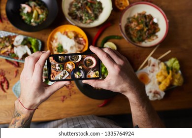 Above View Closeup Of Unrecognizable Man Taking Picture Of Asian Food Dishes, Copy Space