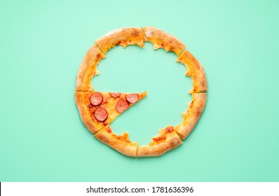 Above View With The Crust And A Single Slice Of A Pepperoni Pizza. Top View With Pizza Leftovers On A Green Colored Background.