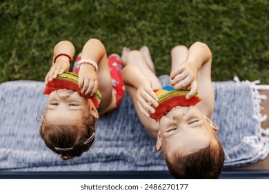 From above view of cute little brother and sister sitting outside and eating juicy watermelon. - Powered by Shutterstock