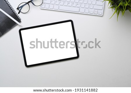 Above view of digital tablet with empty screen on white office desk.