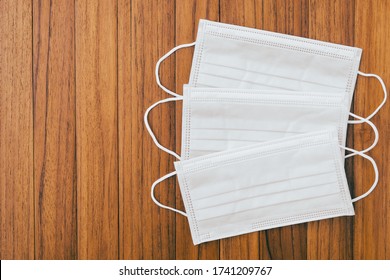 Above View Of Disposable Surgical Mask On Brown Panel Wooden Texture Background. Protective White Medical Face Mask Epidemic Coronavirus Quarantine, COVID-19 With Copy Space On Old Wood Table.Top View