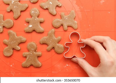 Above view of female hand with cutter making sweet homemade Christmas cookies. Sweet dough for traditional gingerbread man cookies