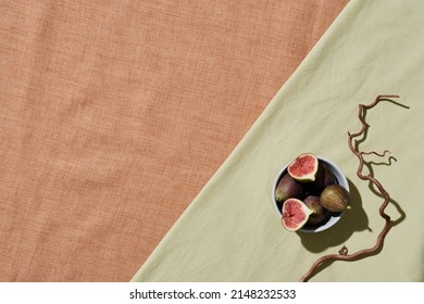 Above View Of Fresh Figs And Slices In Bowl Placed On Edge Of Tablecloth With Twig