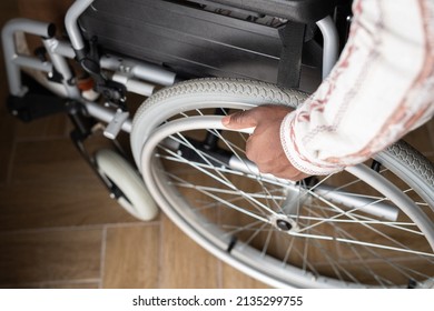 Above View Of Hand Of Young Man With Disability Rotating Wheel Of Wheelchair While Moving Down Wooden Floor