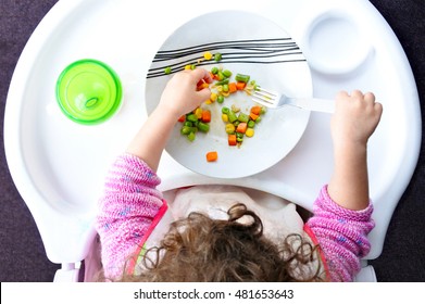 Above view of a little toddler child eats vegetables. Childhood and children health care concept. Real people. copy space