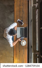 Above View Of Man Using Laptop And Other Hi-tech Devices Such As Smartphone, Tablet, Laptop