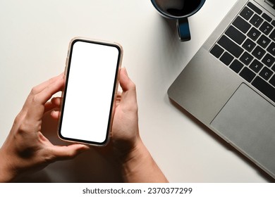 Above view of man using mobile phone over white office desk. Blank screen for your advertising text message.