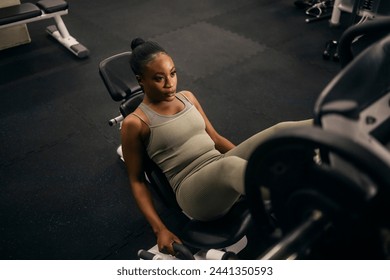 From above view of a muscular african american sportswoman practicing legs on a leg press machine at gym. - Powered by Shutterstock