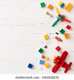 Above view on colorful plastic bricks, toys and red plane on white wooden table background