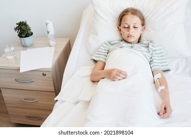 Above view portrait of child laying in hospital bed with oxygen support and IV drip, copy space - Powered by Shutterstock