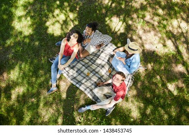 Above View Portrait Of Group Of Friends Enjoying Picnic On Green Grass In Summer And Looking Up At Camera, Copy Space