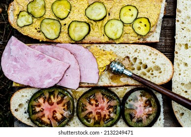 Above View Sandwich Making On White Bread Baguette Halves With Spread Mustard, Pickles, Ham, Heirloom Tomato Slices Drizzled With Honey