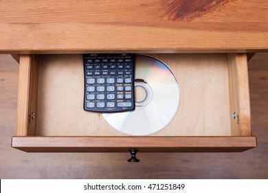 above view of scientific calculator and disk with the experimental data in open drawer of nightstand
