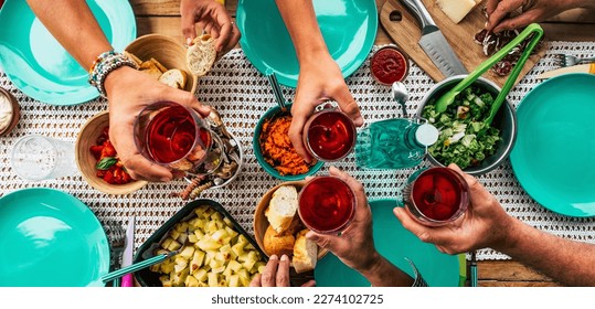 above view of table with group of friends people celebrating and toasting with red wine glasses and eating food all together having fun. Lunch time and friendship. Family celebrate clinking drinking - Powered by Shutterstock