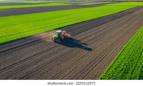 Above view, of tractor as pulling mechanical seeder machine over arable field, soil, planting new cereal crop, corn, maize. - Shutterstock ID 2293112971