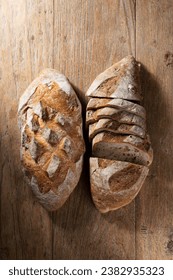 Above view of two rustic loafs of bread on an old wooden table.