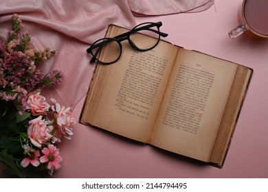 Above view vintage book, eyeglasses coffee cup and spring flowers on pink background. - Powered by Shutterstock