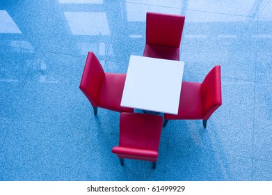 Above view of white table with four red chairs near by.