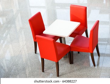Above view of white table with four red chairs near by.