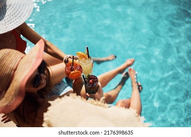 Vista superior de las mujeres que tocan con cócteles de verano en la piscina. espacio de copia. 