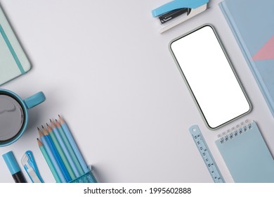 Above view with work space concept, blue color of stationary, blank screen of smartphone and mug of coffee.
