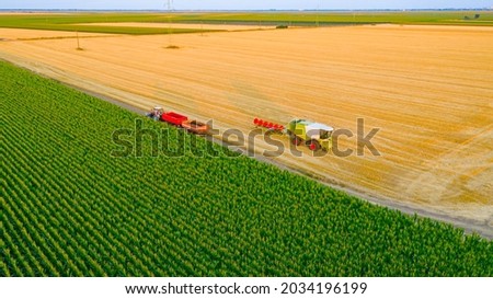 Above view of worker as he removing the leftovers of plants and preparing header of agricultural machine for travel in public traffic.