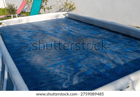 Above-ground pool at the end of winter. The protective cover is dirty.