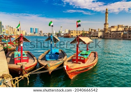 Abra - old traditional wooden boat  and Grand Bur Dubai Masjid Mosque on the bay Creek in Dubai, United Arab Emirates
