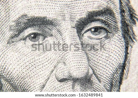 Abraham Abe Lincoln face on 5 dollar bill close up. Detail of new currency note, macro view of eyes on USA paper money. Etched portrait of US president. Concept of  USD cash and dollar banknote.