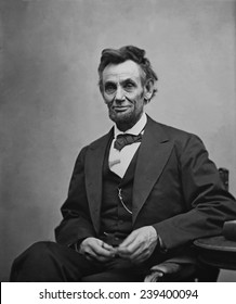 Авраам Линкольн (1809-1865) сидел и держал свои очки и карандаш 5 февраля 1865 в портрете Александра Гарднера.