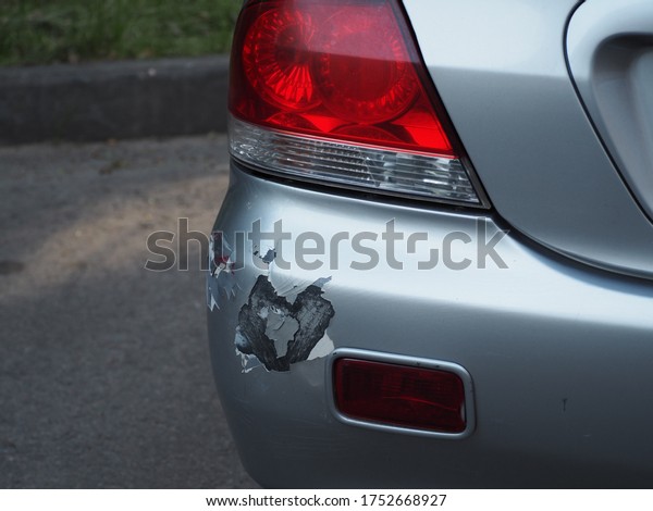 Abrasions and dents on the rear bumper of silver\
car after a slight collision accident. Backside of car get\
scratched, damaged by accident on\
parking