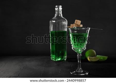 Absinthe, brown sugar and lime on black table, space for text. Alcoholic drink
