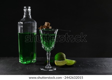 Absinthe, brown sugar and lime on black table, space for text. Alcoholic drink
