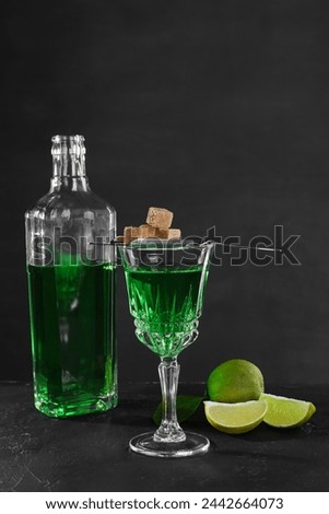 Absinthe, brown sugar and lime on black table. Alcoholic drink