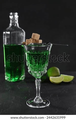 Absinthe in glass, brown sugar and lime on black table. Alcoholic drink