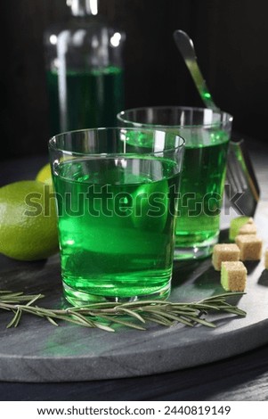 Absinthe in glasses, rosemary, brown sugar and lime on table. Alcoholic drink