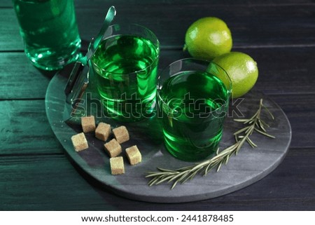 Absinthe in glasses, rosemary, brown sugar and lime on wooden table. Alcoholic drink