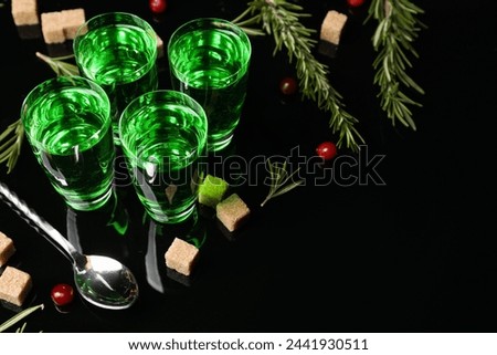 Absinthe in shot glasses, cranberries, rosemary and brown sugar on mirror table, space for text. Alcoholic drink
