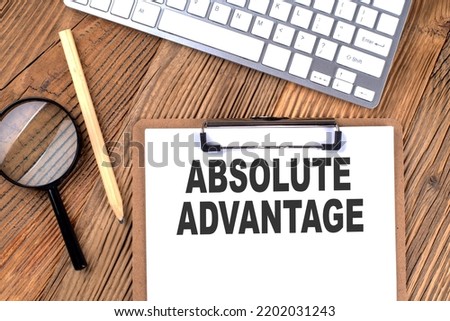 ABSOLUTE ADVANTAGE text on paper clipboard with magnifier and keyboard on a wooden background