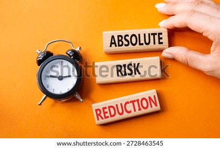 Absolute Risk Reduction symbol. Concept words Absolute Risk Reduction on wooden blocks. Businessman hand. Beautiful orange background with alarm clock. Business and Absolute Risk Reduction concept. Copy space.