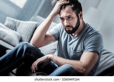 Absolutely hopeless. Depressed unhappy cheerless man holding his forehead and thinking what to do while being in a hopeless situation - Shutterstock ID 1060449164