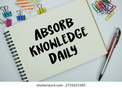 Absorb Knowledge Daily text message written on notepad with stationery flat lay on white background