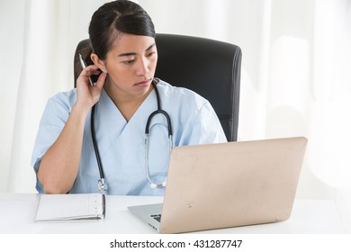 Absorbed Asian Female Doctor Working At Computer